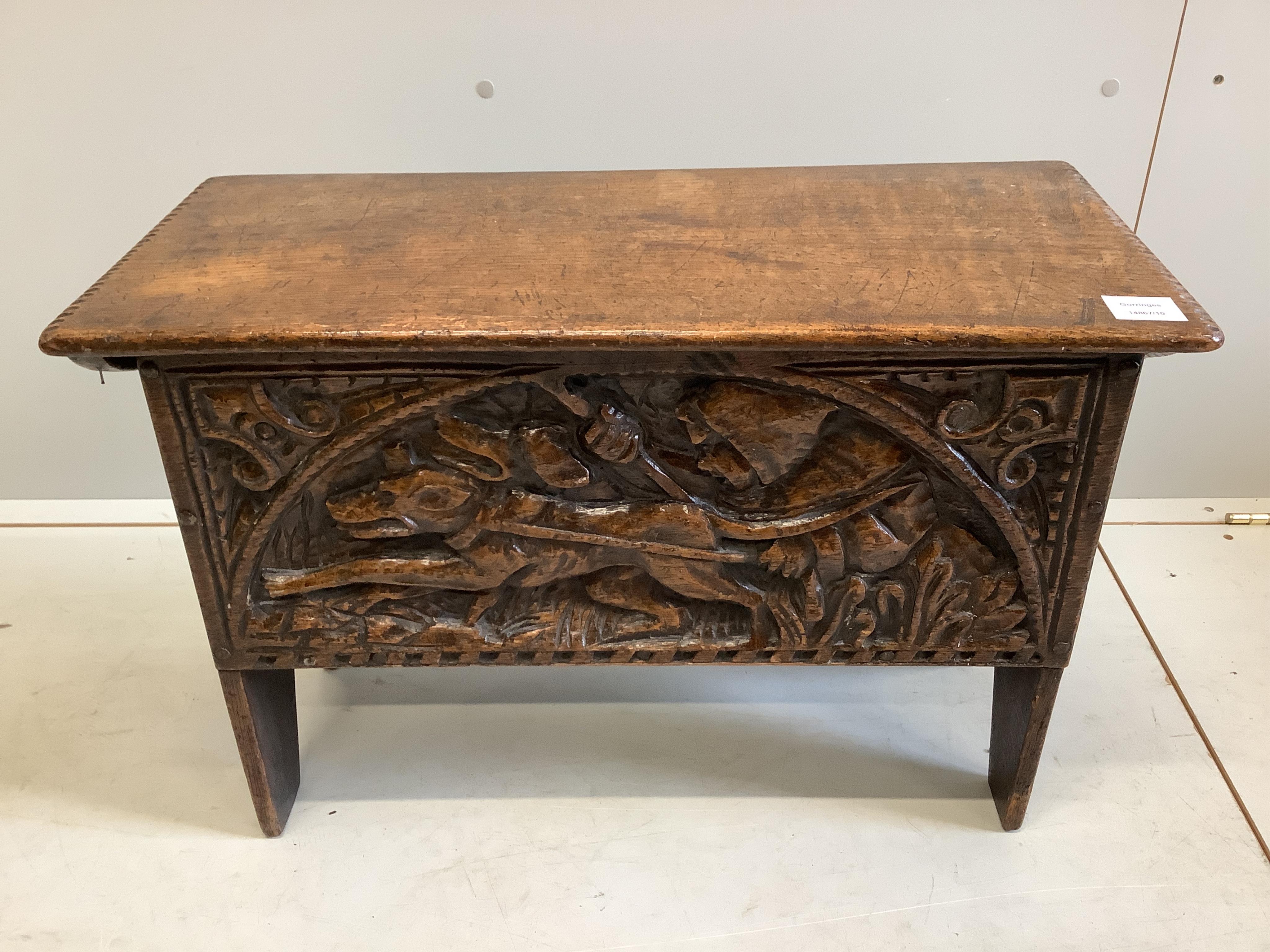 A small reproduction Tudor style oak coffer, the front carved with hunting hounds and foliage, width 67cm, depth 30cm, height 45cm. Condition - good